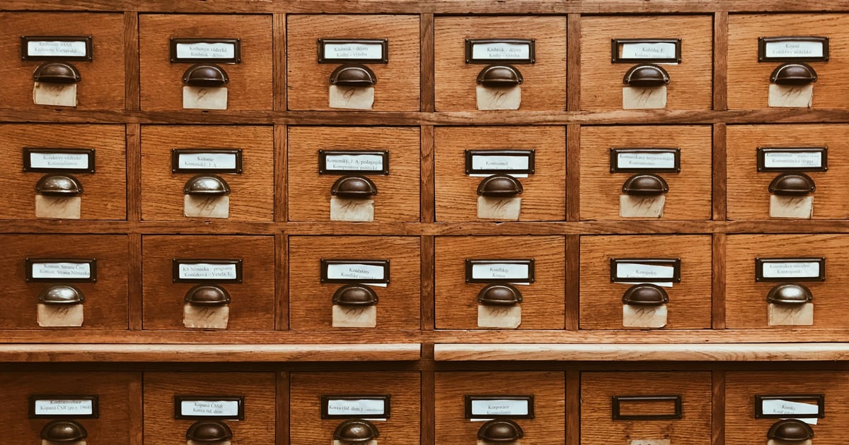 An open wooden card catalogue drawer packed with index cards.