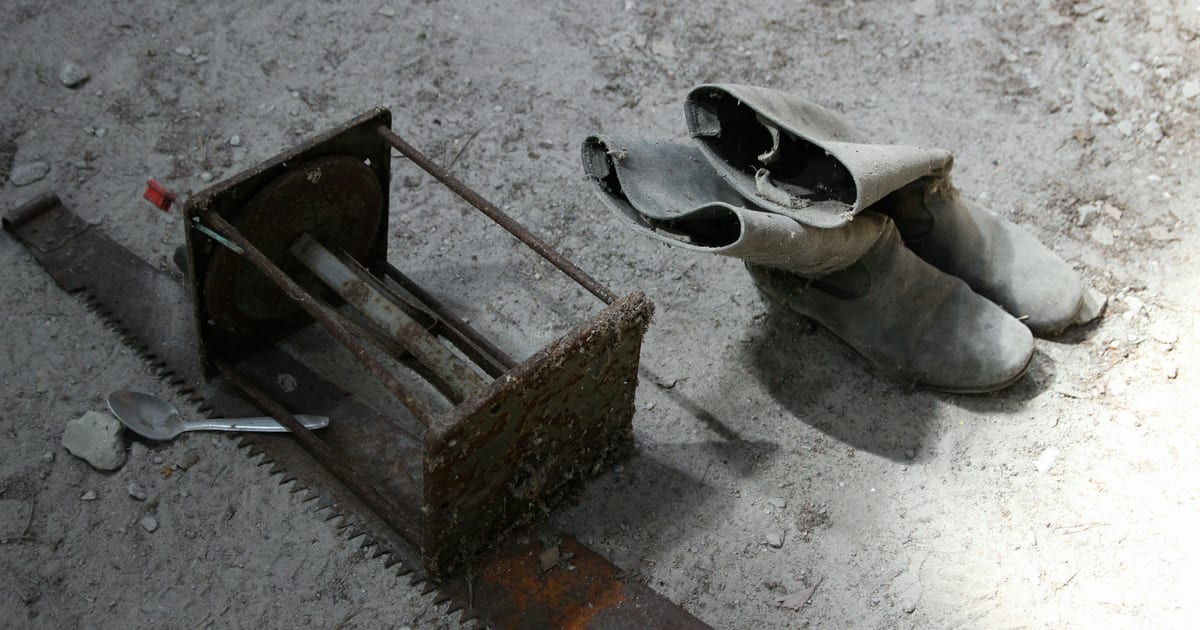 A pair of unworn grey knee-high boots standing on a plain floor.