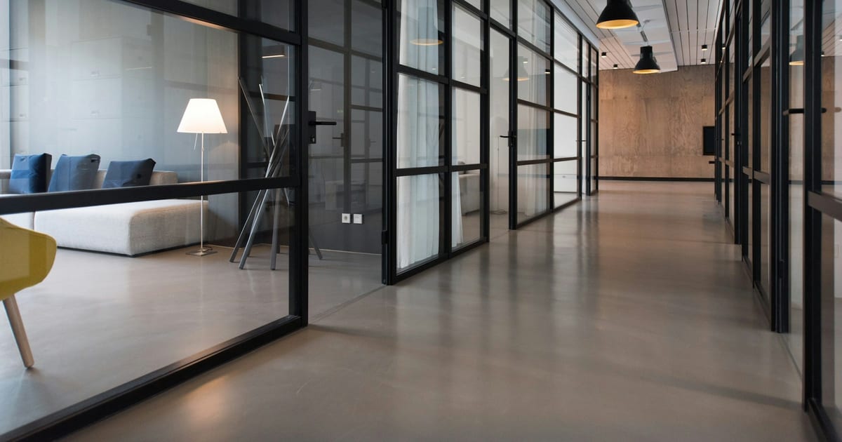 An office corridor running between glass-panelled doors.