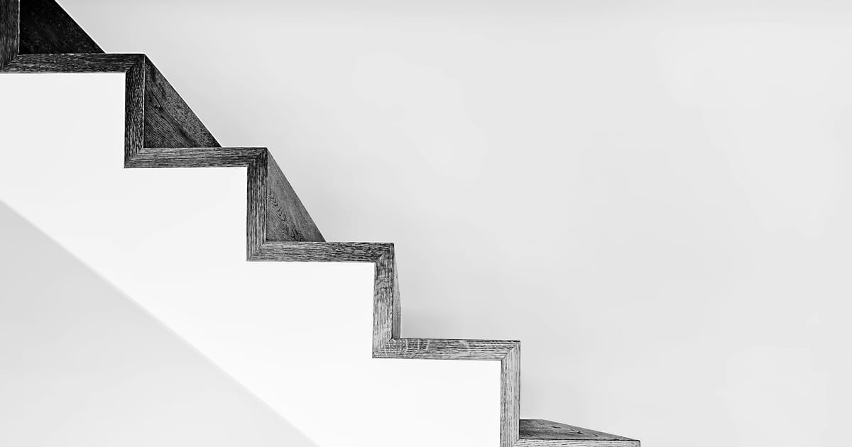 A flight of white concrete stairs with a black metal railing.