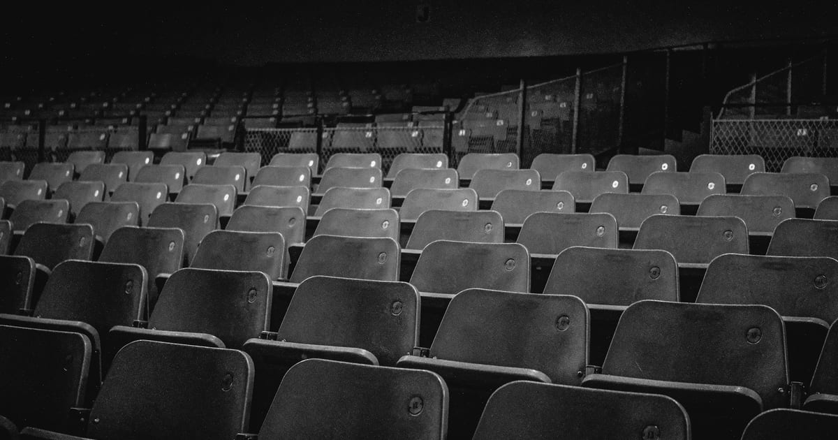 Rows of empty stadium seats in black and white.