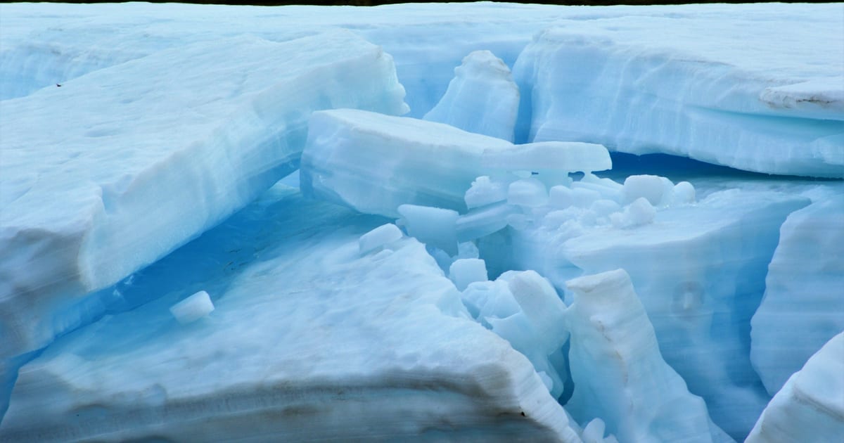Cracked sheet ice over dark blue water.