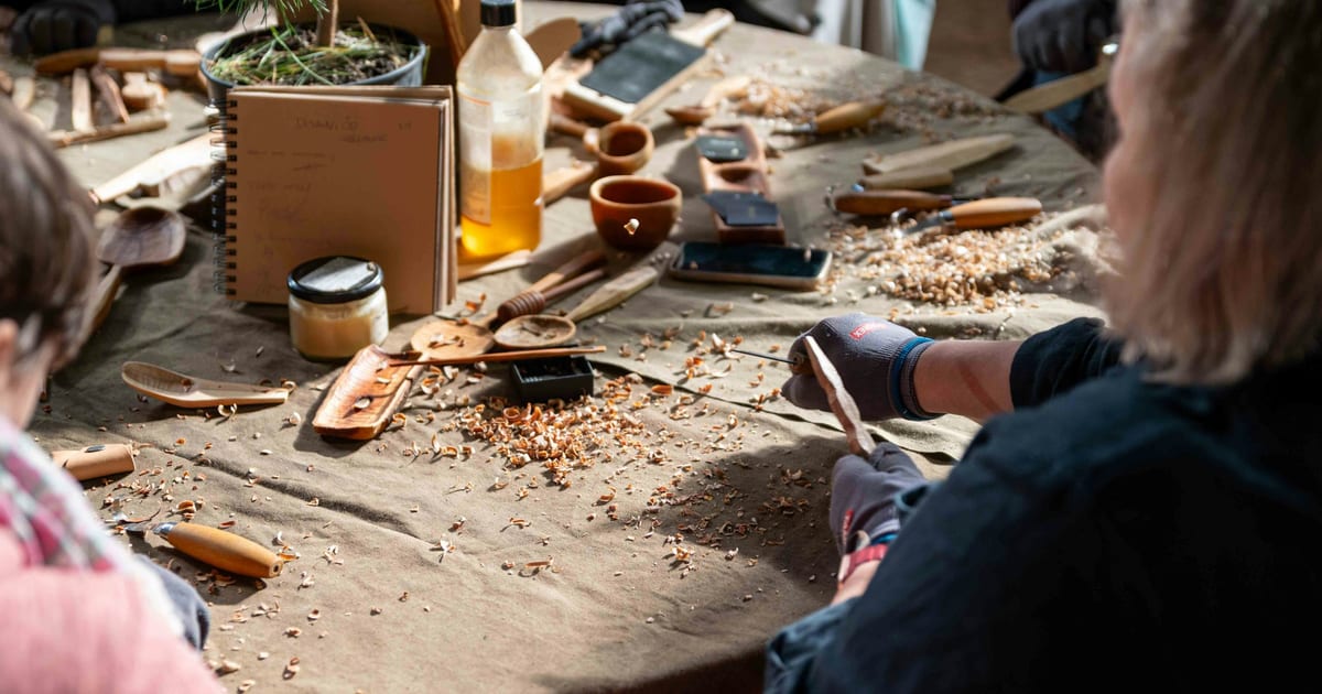 Several people working with hand tools around a wooden bench in a workshop.